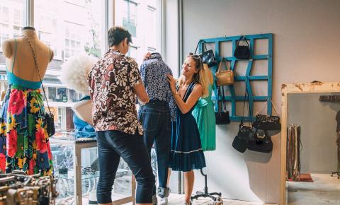 Fashion merchandiser works with retail professional to dress a store window display.