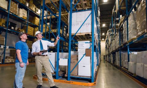 Supply chain manager discusses logistics with a warehouse worker.
