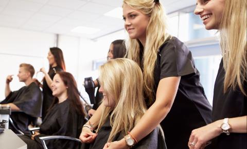 Hairstylist-in-training checking the evenness of cut lengths during an in-class session.
