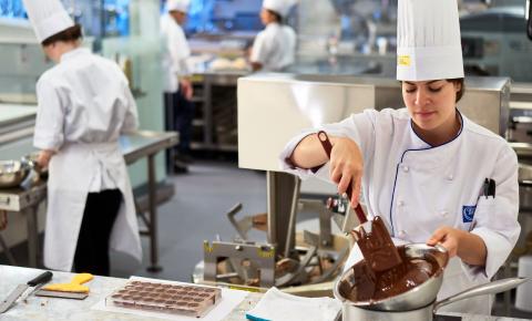 Baking arts students working with chocolate in a culinary lab.
