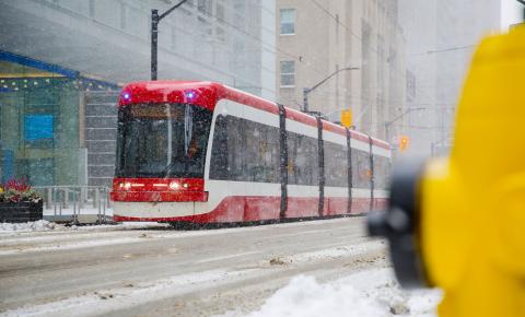 A Toronto street car traversing through the city during a snowstorm.