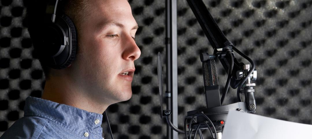 Voice actor reading in front of a microphone in a sound studio.