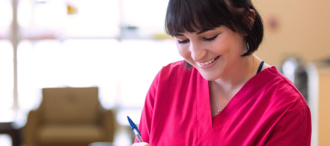 Nurse writes in a medical chart at a facility.